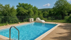 Ein rechteckiger Swimmingpool mit klarem, blauem Wasser, umgeben von einem Metallzaun und einem Kiesbereich.