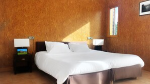 Ein Schlafzimmer mit einem großen Bett, zwei Nachttischen mit Lampen, einem Fernseher auf einem Tisch und einem Fenster an der Wand.