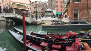 Un canal con góndolas amarradas, un puente y edificios con balcones.
