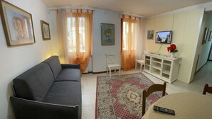 Una sala de estar con un sofá, una mesa de comedor, un televisor y un aparador.