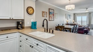 Una cocina moderna con un lavamanos doble, armarios blancos y un comedor con mesa y sillas.