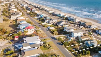 An aerial view of a coastal residential area with houses and a road leading to the beach.