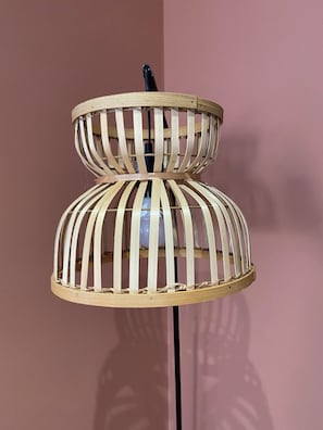 A wooden, two-tiered, cylindrical floor lamp with a black base.