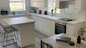 A modern kitchen with a central island, white cabinetry, and a built-in oven.