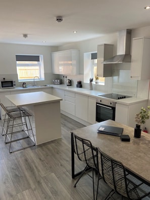 A modern kitchen with a central island, white cabinetry, and a built-in oven.