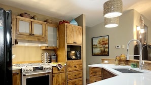 Una cocina moderna con armarios de madera, electrodomésticos de acero inoxidable y encimera blanca.