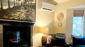 Un salón con chimenea, un sofá, una mesa de centro y un cuadro en la pared.