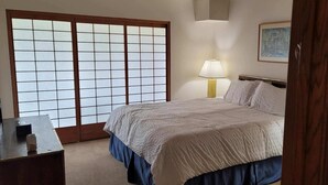 A bedroom with a bed, a nightstand with a lamp, a wooden desk, and a shoji screen door. - Gorgeous, sweeping views of Lake Tahoe from 3 story lake front condo! (Tahoe City)