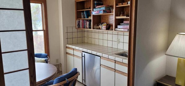 Une cuisine compacte avec un dosseret carrelé, des meubles en bois et une bibliothèque intégrée.