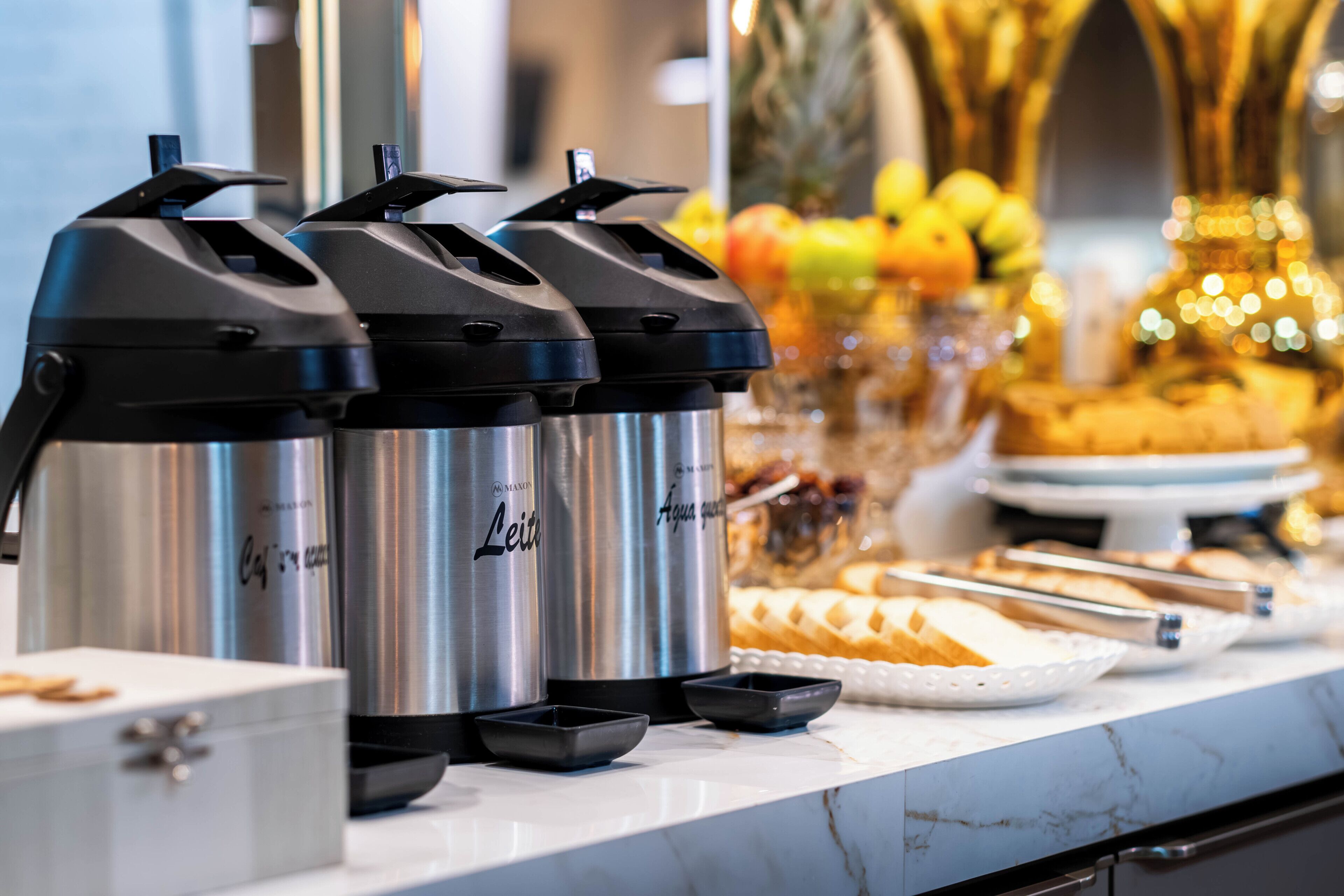 Montaje de bufé con dispensadores de bebidas de acero inoxidable etiquetados como 'Leit' y una variedad de alimentos.