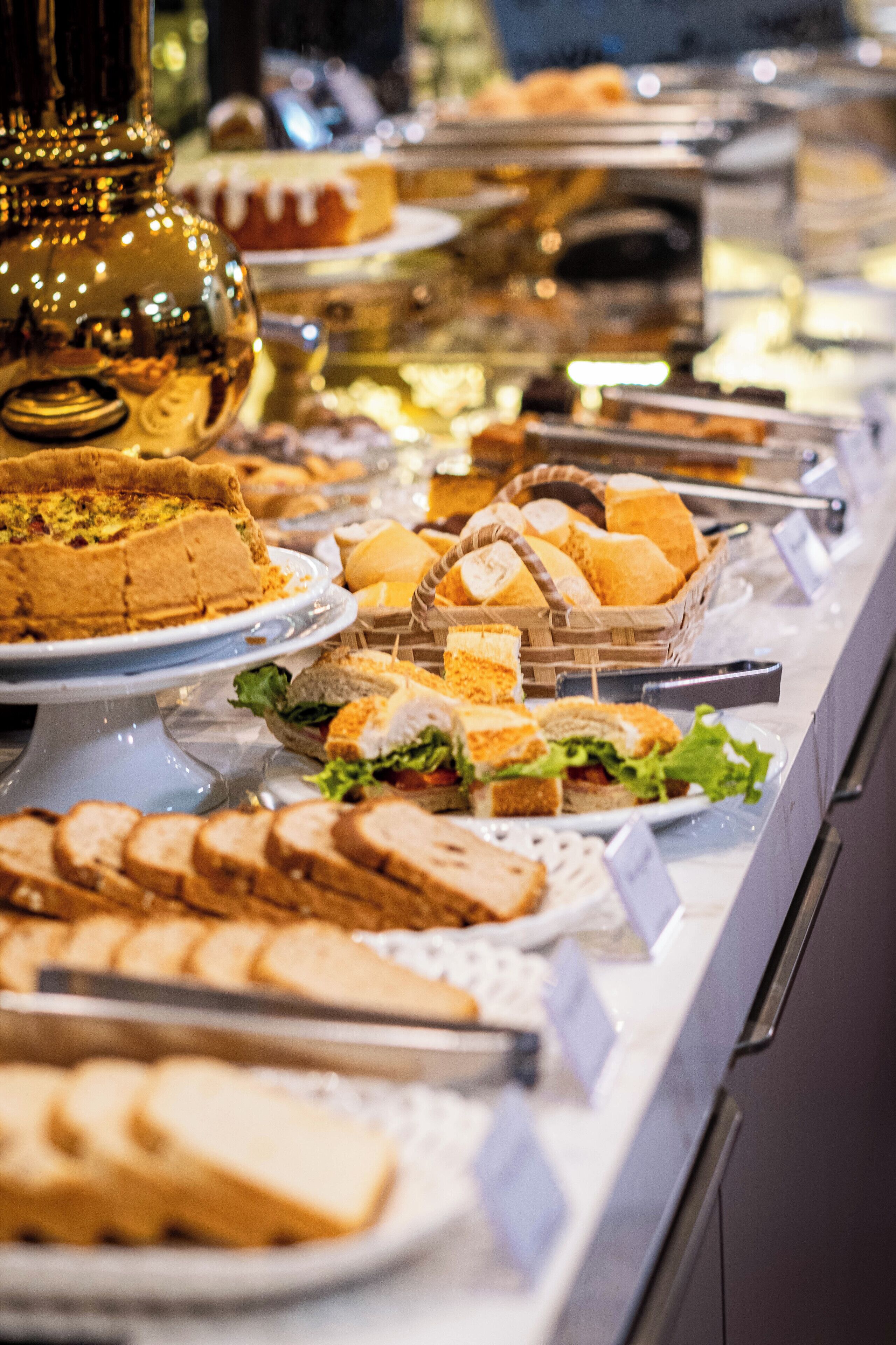 A buffet with various food items including sandwiches, bread, and a cake.