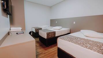 A hotel room with two beds, a desk, and a flat-screen TV.