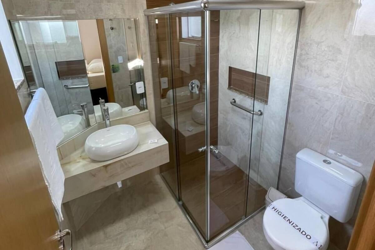 Un baño moderno con ducha de vidrio, tocador doble y retrete.