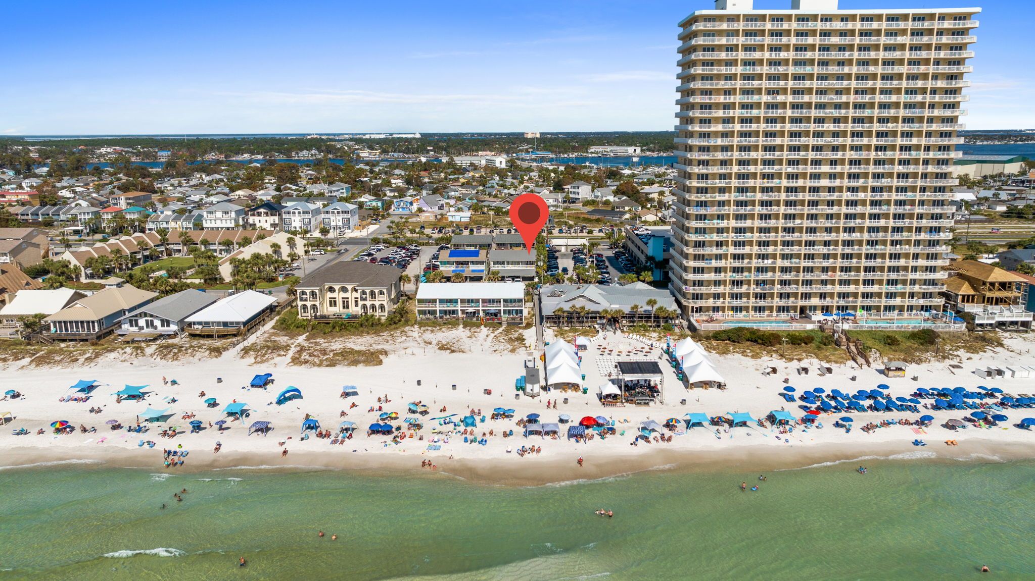 A coastal hotel with multiple floors, a beach in front, and a view of the ocean.