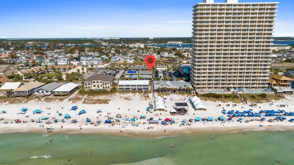 A coastal hotel with multiple floors, a beach in front, and a view of the ocean.
