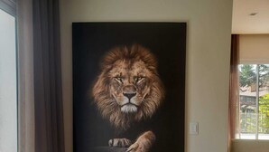 Una gran pintura realista de un león en una pared de una habitación con ventana.