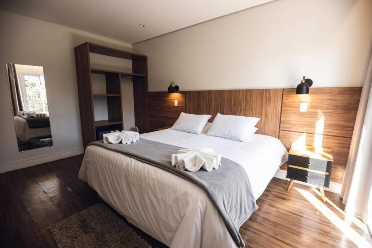 Una habitación de hotel moderna con una cama grande, cabecera de madera, lámparas de noche y un armario empotrado.