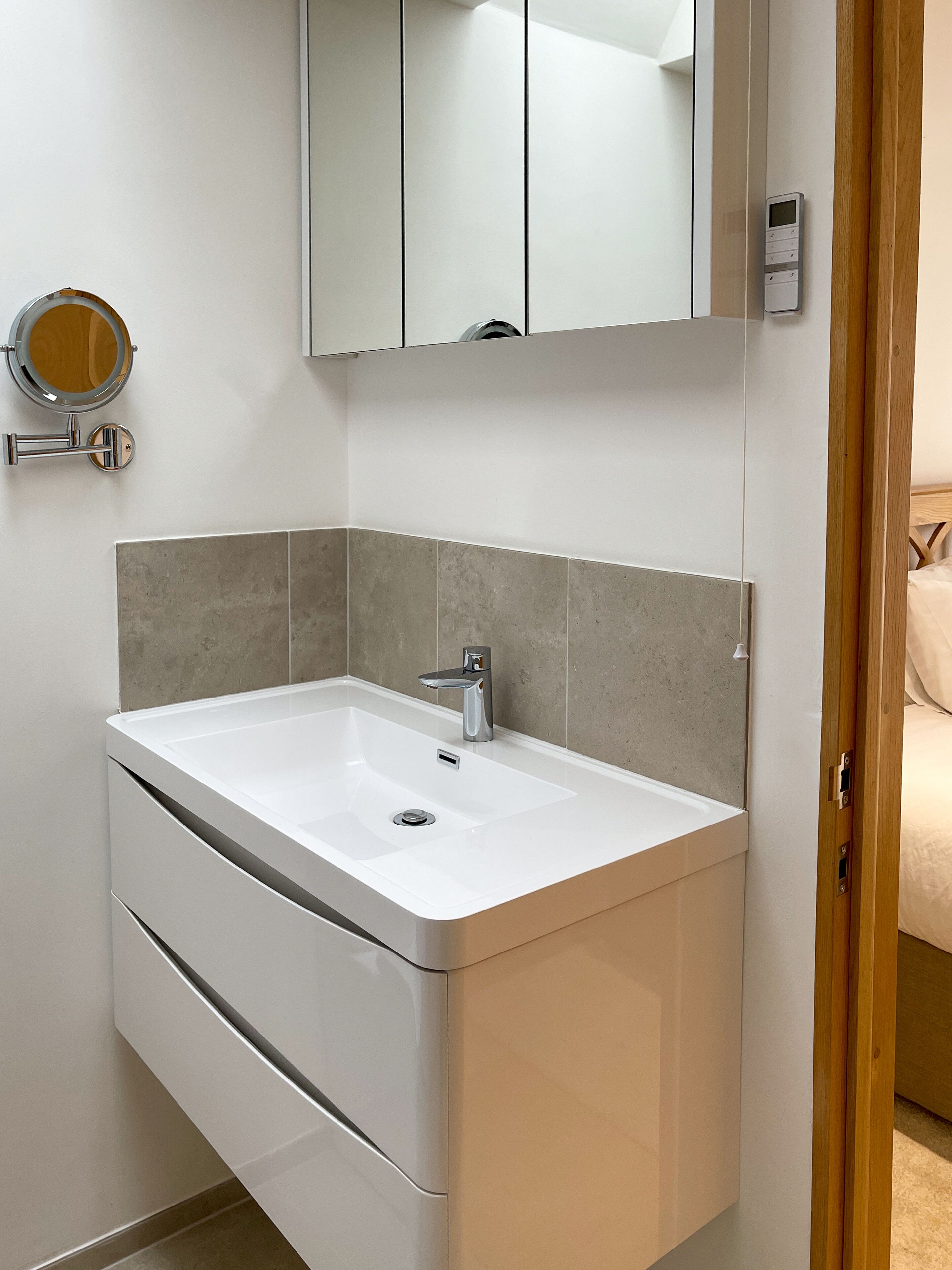 Un baño moderno con un lavamanos blanco, un espejo y un inodoro.
