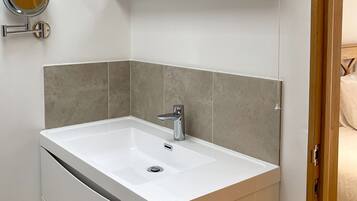 Un baño moderno con un lavamanos blanco, un espejo y un inodoro.