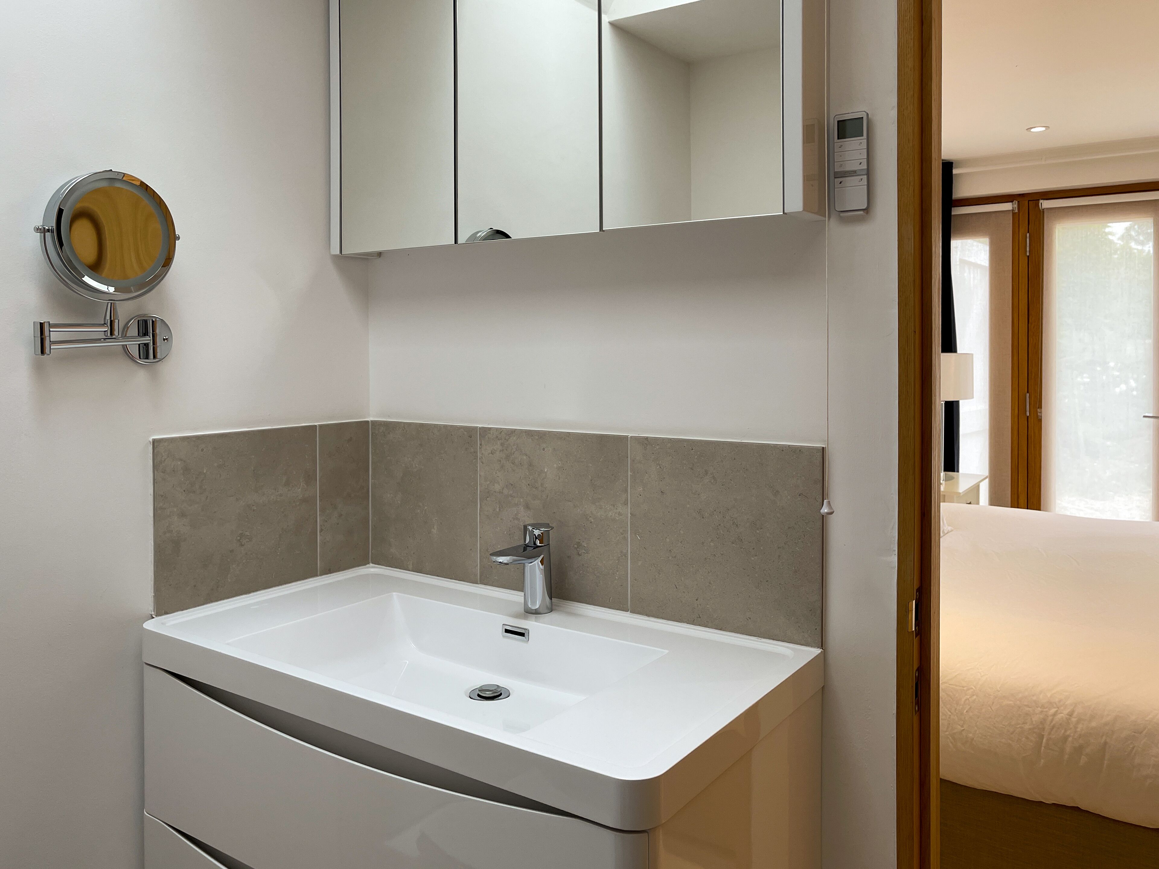 A modern bathroom with a white sink, a mirror, and a toilet.