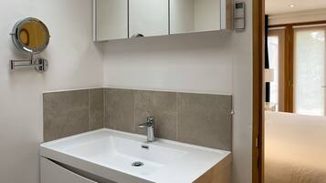 A modern bathroom with a white sink, a mirror, and a toilet.