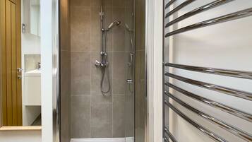 A modern shower area with a glass door, a showerhead, and a hand shower.