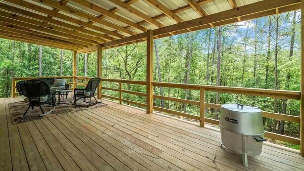 A covered outdoor deck with wooden flooring, metal railings, and a grill. - Cozy Cottage in Rayburn Country-Pet Friendly-King Suite/Pool Table! Sleeps 10 (Brookeland)