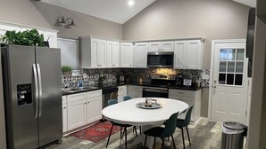 A modern kitchen with white cabinets, a stainless steel refrigerator, a microwave, and a coffee machine. - Cozy Cottage in Rayburn Country-Pet Friendly-King Suite/Pool Table! Sleeps 10 (Brookeland)