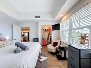 A bedroom with a bed, a vanity with a mirror, a chair, and a dresser.