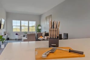 Eine Küchenarbeitsplatte mit Messer und Schneidebrett, ein Messerblock mit Messern und ein Fenster mit Blick ins Freie.