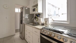 Una cocina moderna con refrigerador de acero inoxidable, microondas, estufa a gas y muebles de cocina blancos.