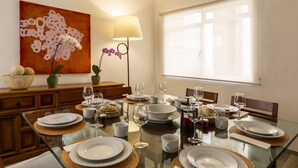Comedor con mesa de vidrio dispuesta para una comida, rodeado de sillas de madera.