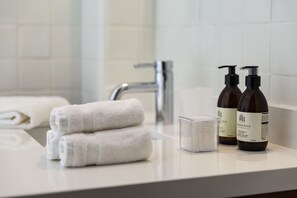 Een bad/douchecombinatie, een haardroger, handdoeken, zeep