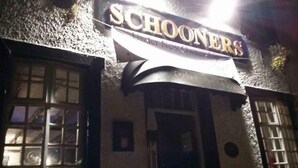 A building with a sign reading "Schooners" and a curved awning above the entrance. - Stunning 2-bed Apartment Above Schooners Bar (Neath)