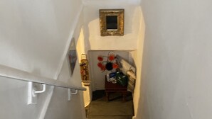 A staircase with a handrail, leading to a landing with a small table and a mirror. - Stunning 2-bed Apartment Above Schooners Bar (Neath)