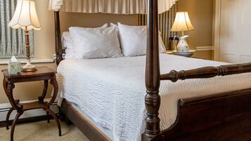 A four-poster bed with a canopy, two bedside tables with lamps, and a carpeted floor.