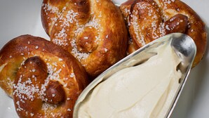 Um prato com três doces e uma colher de chantilly.