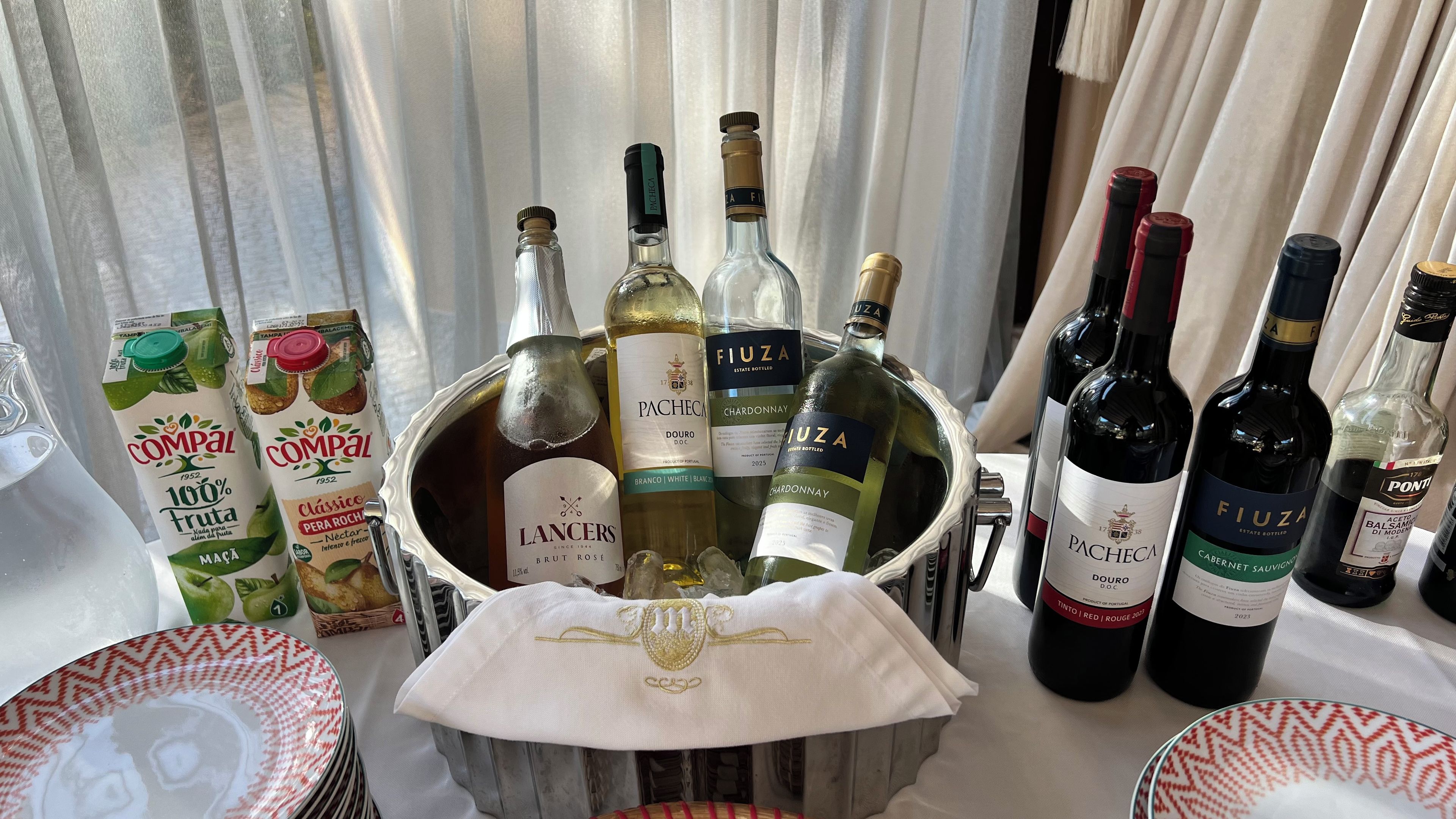 A collection of wine bottles and juice cartons on a table with a white cloth napkin.