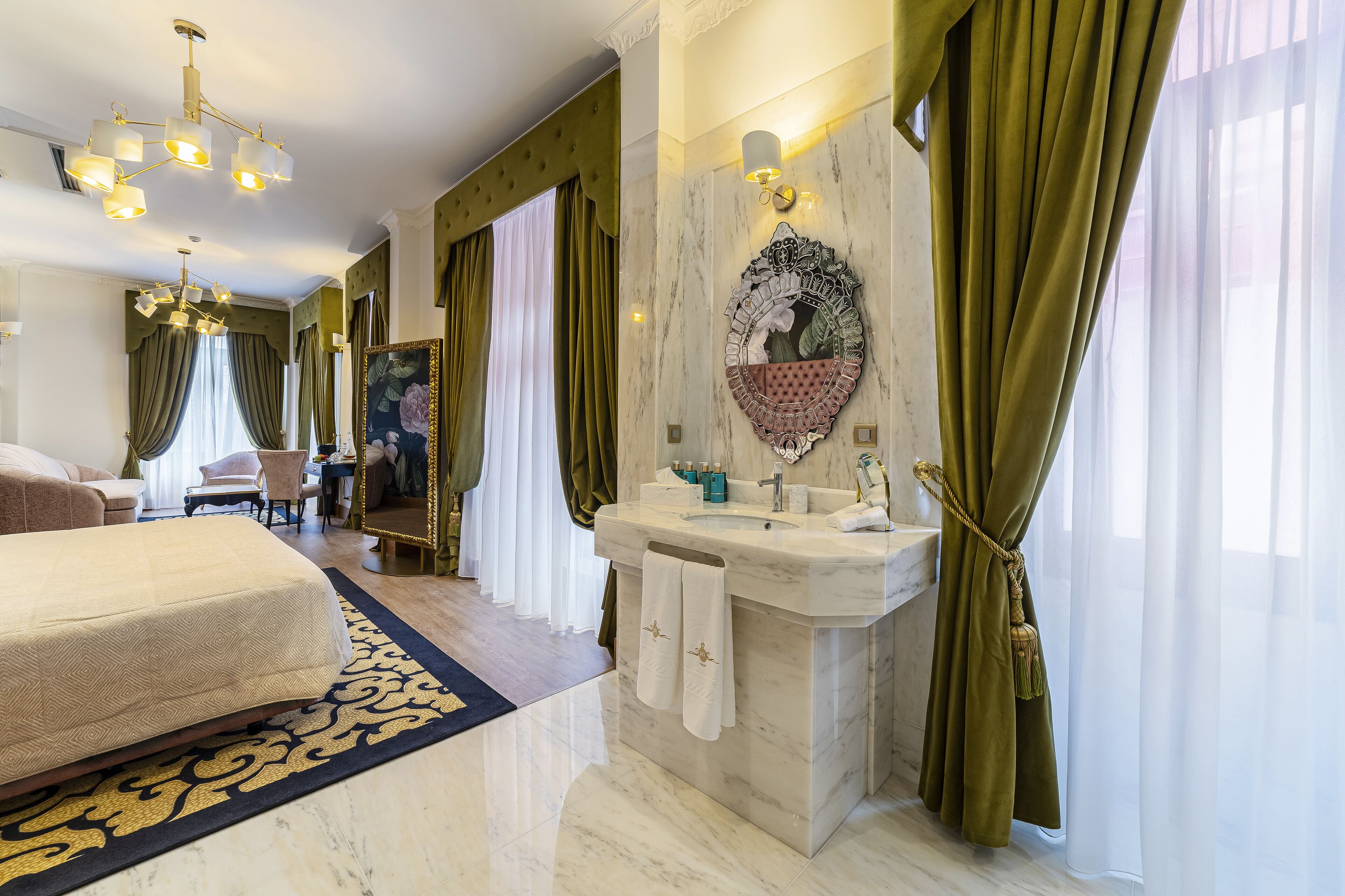 A hotel room with a bed, a bathroom with a marble sink, and green curtains.