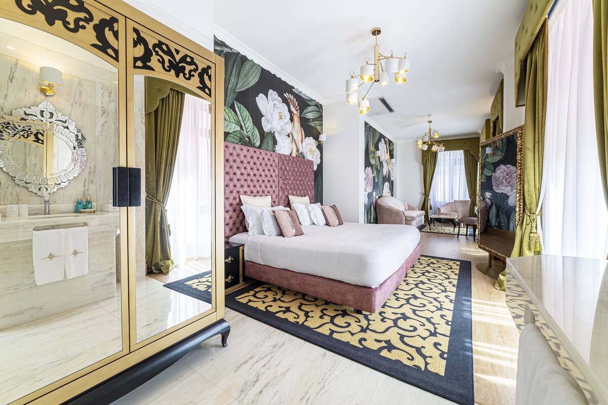 Un dormitorio lujoso con una cama grande, un tocador de mármol y un mural floral.