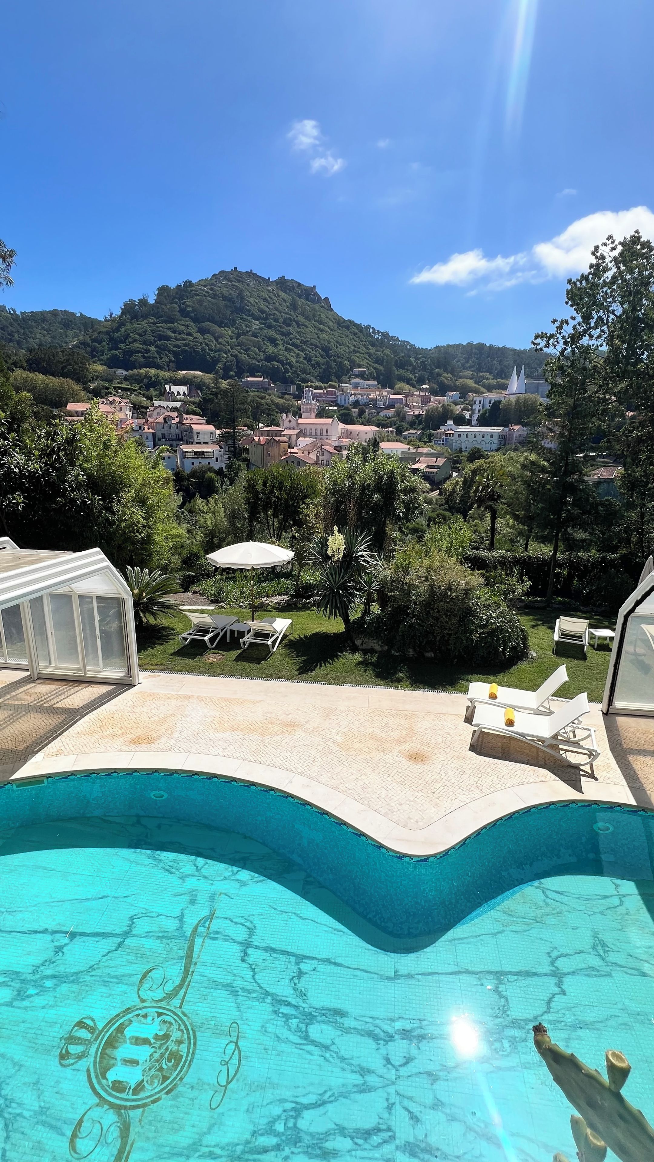 Una piscina con vistas a un pueblo y colinas al fondo.