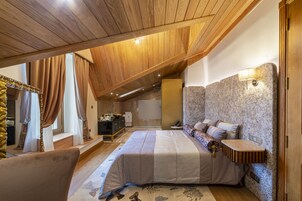 Un dormitorio con cama, mesita de noche, lámpara de pared y techo de madera.