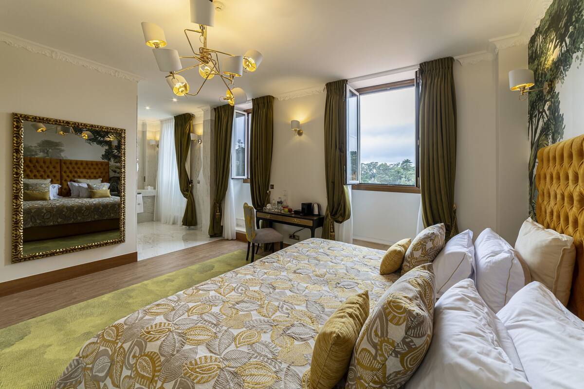 Habitación de hotel con una cama grande, un escritorio, una silla, un espejo y vistas al exterior.