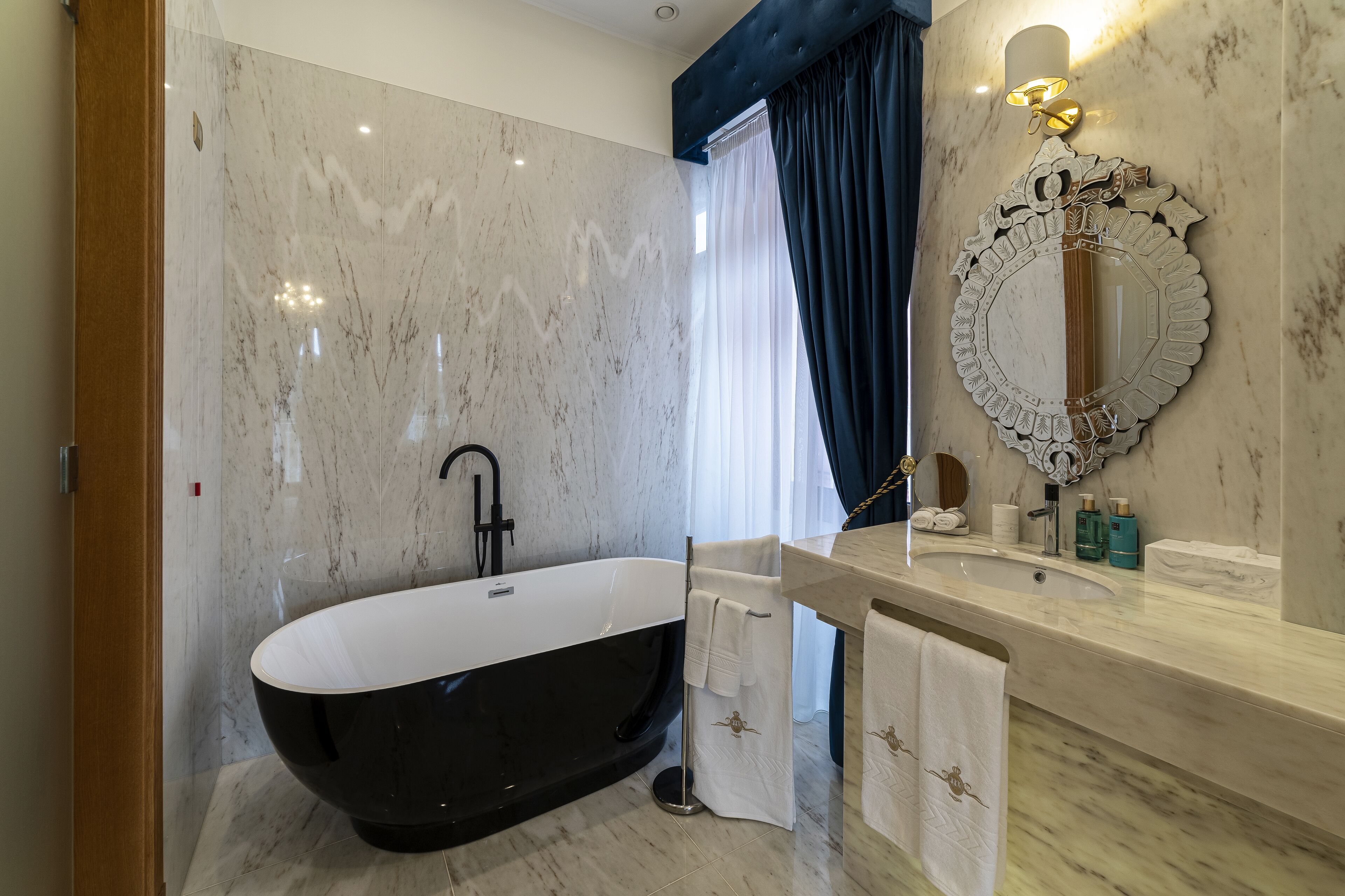 A modern bathroom with a freestanding bathtub, a vanity with a mirror, and a shower curtain.