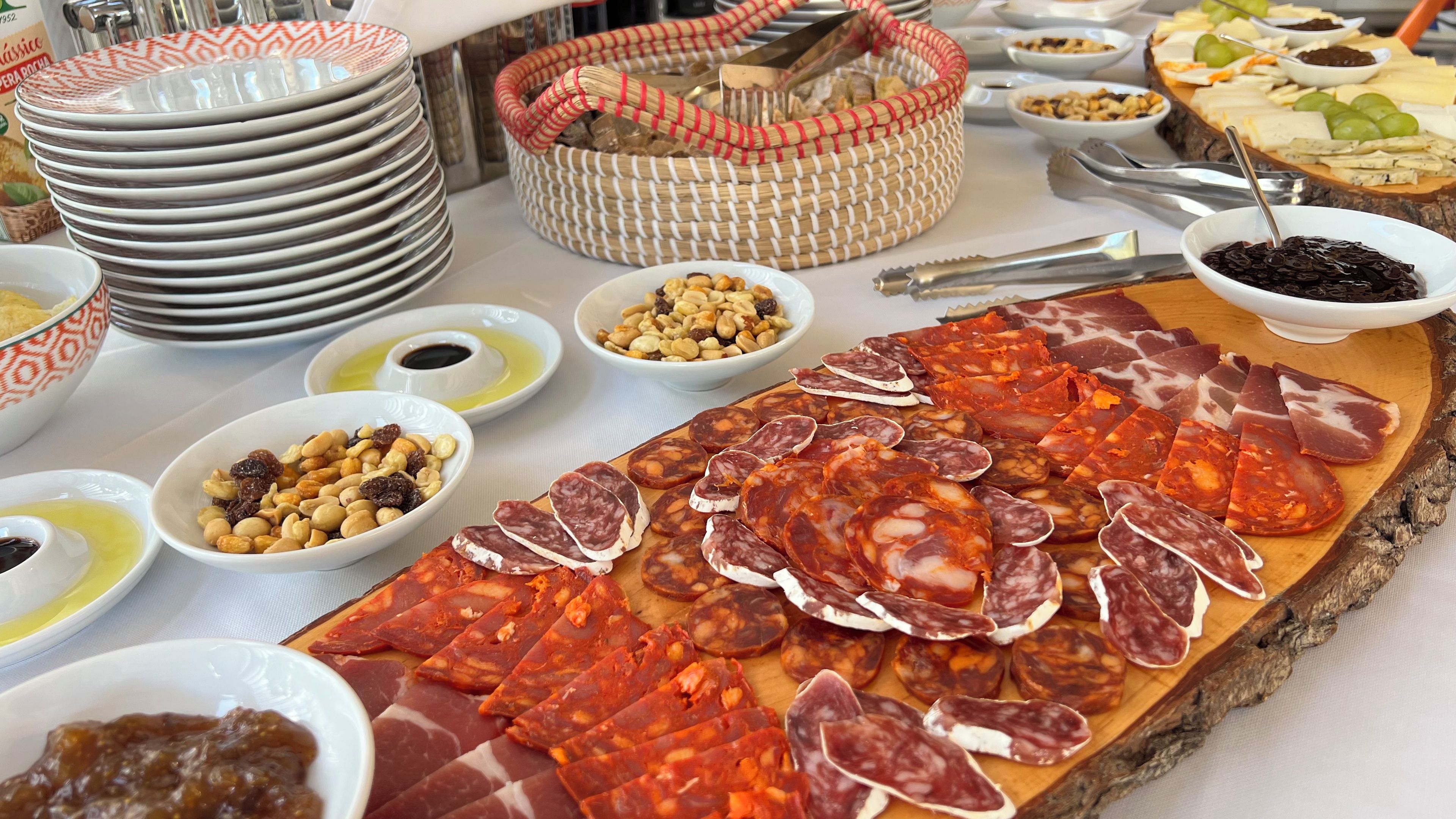 Une planche de charcuterie avec différentes sortes de viandes et de noix, accompagnée de petits ramequins de condiments.