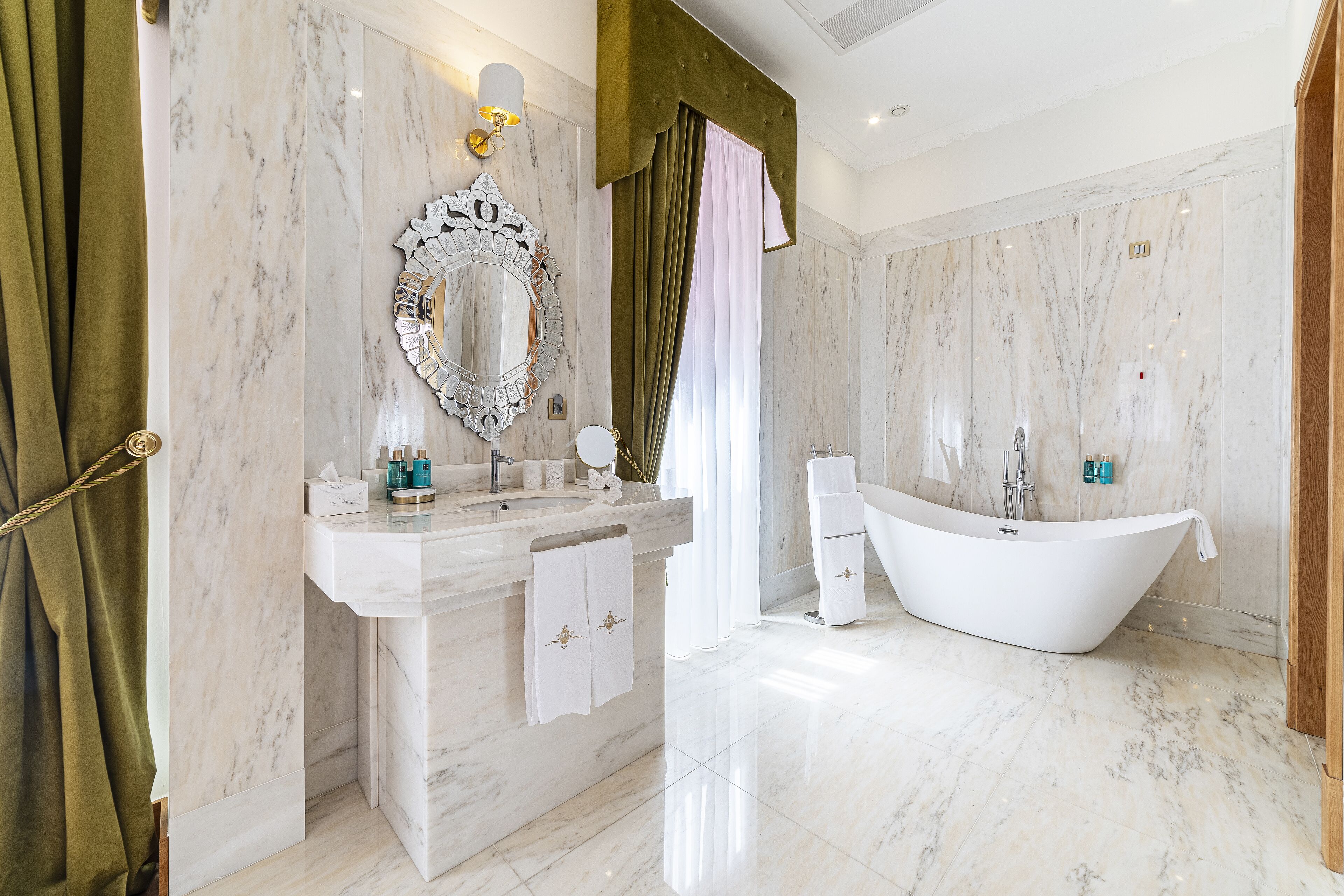 A modern bathroom with a freestanding bathtub, a large mirror, and a marble vanity.