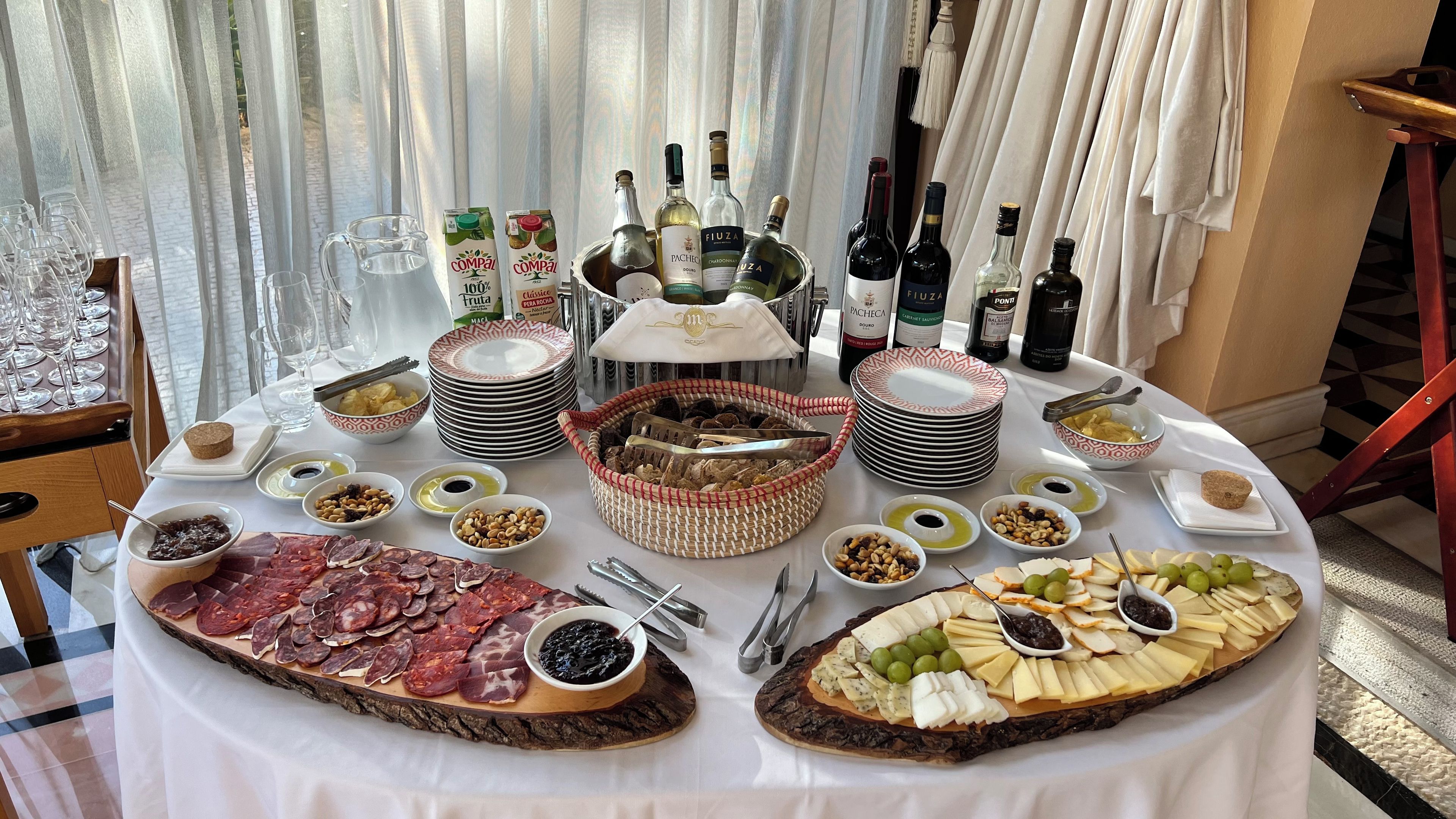 Un tavolo rotondo con una varietà di cibi, tra cui carni, formaggi e frutta, e diverse bottiglie di vino.
