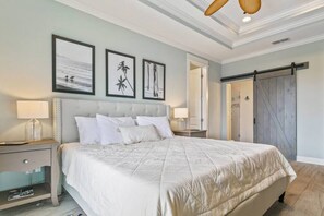 A bedroom with a large bed, two bedside tables with lamps, a wardrobe with a sliding door, and three framed pictures on the wall.