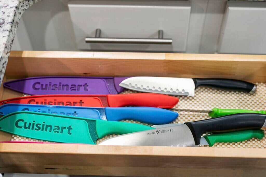 A drawer containing various kitchen knives with handles labeled "Cuisinart."