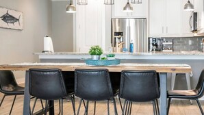 Una cocina moderna con una isla central, sillas negras e iluminación colgante.